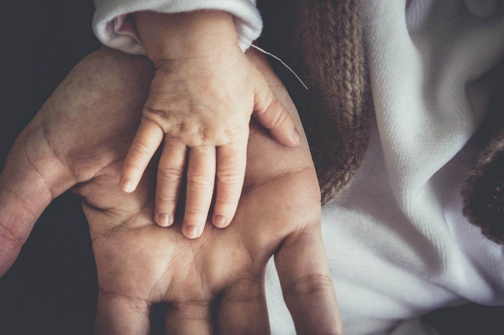 mains adulte et bébé l'une au dessus de l'autre