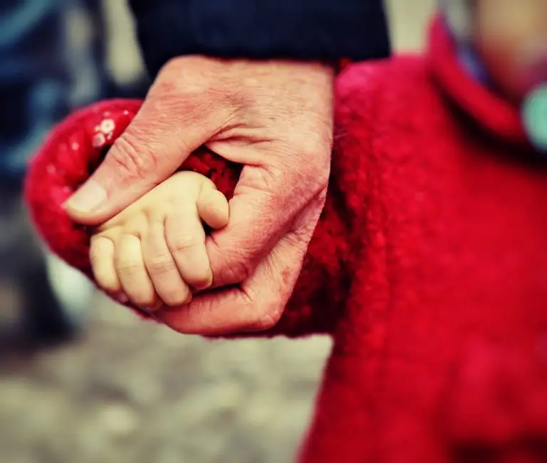 main personne âgée tenant la main d'un bébé