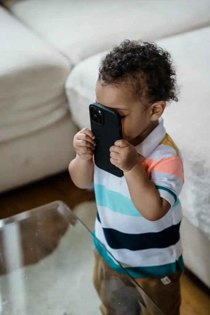 petit garçon-tenant téléphone portable- contre son visage