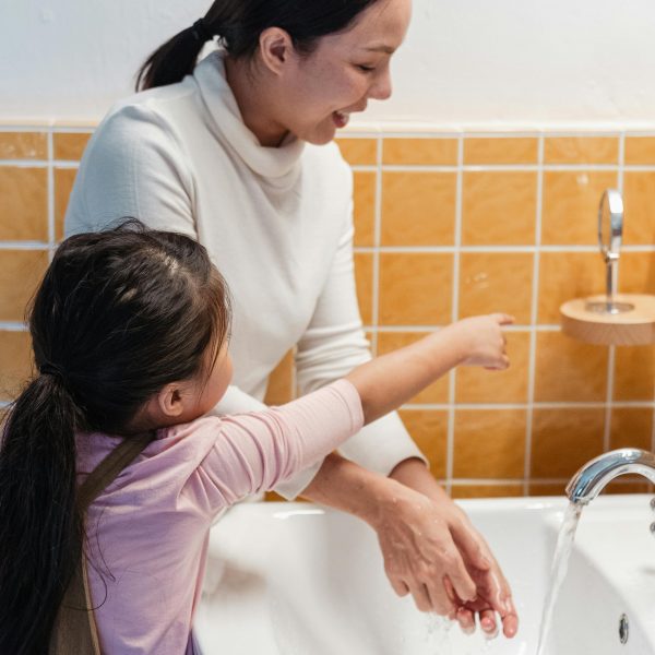 Une mère et sa fille dans une salle de bain. La mère souriante et la fillette pointe du doigt un miroir.