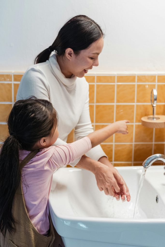 Une mère et sa fille dans une salle de bain. La mère souriante et la fillette pointe du doigt un miroir.