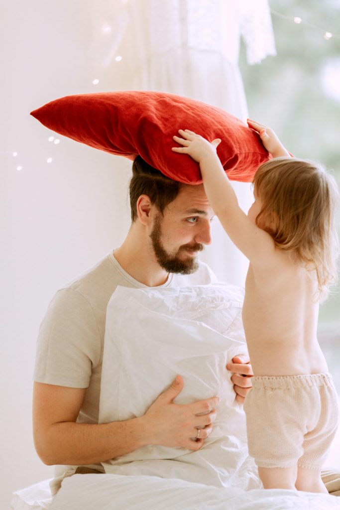 Enfant posant un oreiller rouge sur la tête de son père
